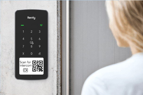 woman uses an access panel with intercom thats mounted on the wall