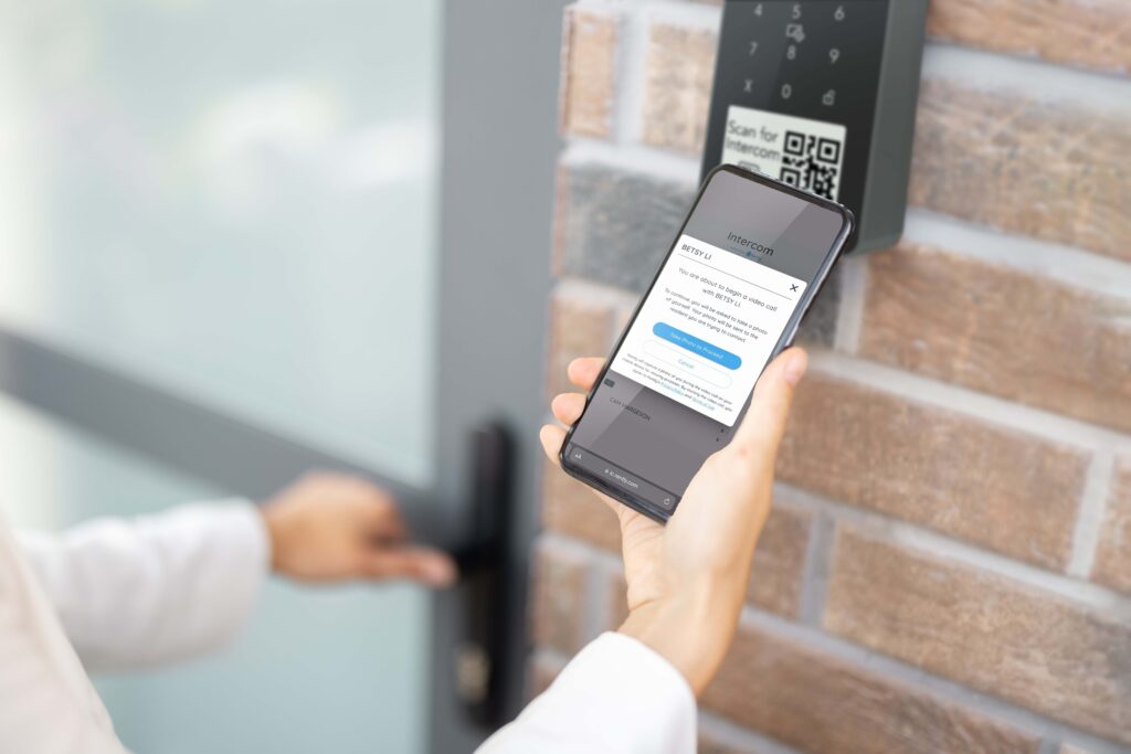 Person using smartphone to access virtual resident directory at a building entrance
