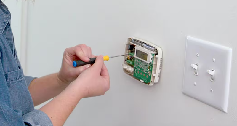 person installing a thermostat